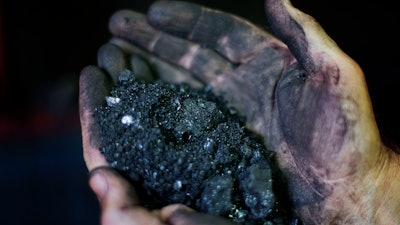 In this Oct. 6, 2015, file photo, Superintendent Jackie Ratliff, a coal miner, holds coal running through a processing plant in Welch, W.Va. For the long-suffering communities that depend on coal, a recent Supreme Court ruling temporarily blocking greenhouse gas reductions was seen as a rare victory.