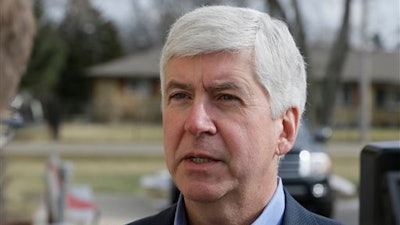 In this Friday, Feb. 5, 2016 file photo, Michigan Gov. Rick Snyder is interviewed after visited a church that's distributing water and filters to its predominantly Latino parishioners in Flint, Mich. Snyder will propose spending $195 million more to address Flint’s water crisis and another $165 million updating infrastructure across the state in response to lead contamination overwhelming the city. (AP Photo/Carlos Osorio, File)