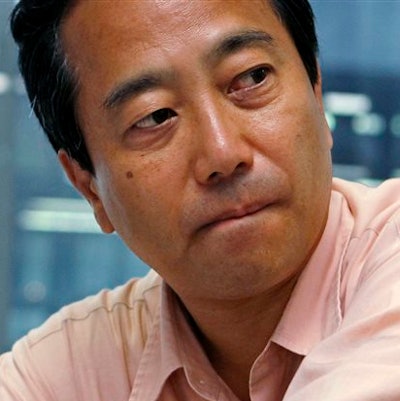 In this July 29, 2013 file photo, Masaharu Hamada, an employee of Japanese medical- device maker Olympus Corp., listens to his lawyer during an interview in Tokyo. The corporate whistleblower's eight-year courtroom battle against Olympus has ended with a financial settlement and a promise from the company to end its harassment of the man. Hamada and the company reached the settlement Thursday, Feb. 18, 2016, which awarded Hamada 11 million yen ($110,000). Legal settlements for individuals in Japan are typically small.