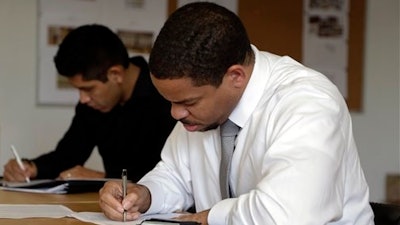 In this Wednesday, Jan. 27, 2016, photo, Reece Lightner fills out a job application for a server at a job fair held by The Genuine Hospitality Group, in Miami, as the restaurant group is expanding in South Florida and hiring for all positions at its restaurants. On Tuesday, Feb. 9, 2016, the Labor Department reports on job openings and labor turnover for December. (AP Photo/Lynne Sladky)