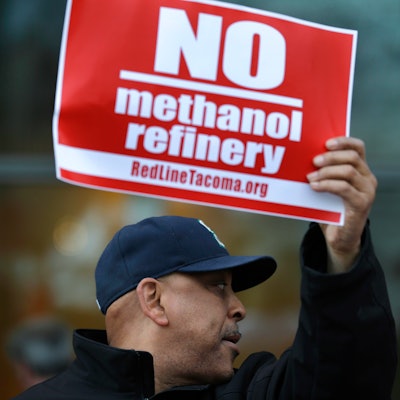Seth Hill, of Tacoma, Wash., holds a sign as he protests in Tacoma outside a public meeting to gather opinion on a proposed methanol plant that would be built at the Port of Tacoma.