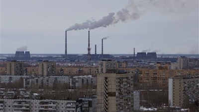 In this photo taken Wednesday, Feb. 17, 2016, buildings of the AvtoVAZ car plant is seen above the residential buildings at the bottom of chimneys in the southern city of Togliatti on the Volga River, Russia. Once intended as a Soviet rival to the capitalist symbol of Detroit, Russia’s auto-making hub is sliding into economic depression.