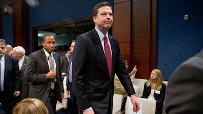 FBI Director James Comey, center, departs following a House Intelligence Committee hearing on world wide threats on Capitol Hill in Washington, Thursday, Feb. 25, 2016. Comey says Apple had been 'very cooperative' in the dispute and that there have been 'plenty' of negotiations between the two sides.