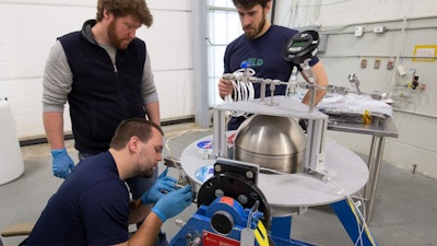 A Goddard team, led by engineer Henry Mulkey (middle), prepares a tank containing a Swedish-developed green propellant before its simulated loading at the Wallops Flight Facility late last year. Kyle Bentley (squatting) and Joe Miller (standing to the right of Mulkey) assisted in the demonstration.