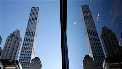 A building at 432 Park Avenue is reflected in another skyscraper in Manhattan, New York, Thursday, Feb. 18, 2016. The last few years have seen the rise of the supertall, a building standing more than 300 meters high. New technologies have allowed the buildings to have footprints no more than the width of a brownstone or two, a far cry from the massive city block an older building like the Empire State Building requires.