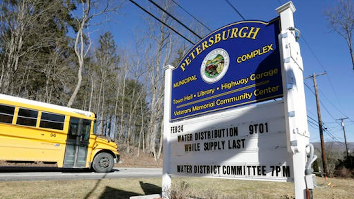 In this Friday, Feb. 26, 2016 photo, a sign outside the Petersburgh Municipal Complex informs residents of water distribution times in Petersburgh, N.Y. PFOA, long used in the manufacuring of Teflon pans, Gore-Tex jackets, ski wax, and many other products has turned up in the water in factory towns around the country like Petersburgh, impacting drinking water.