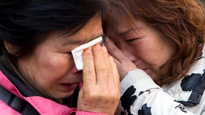 Relatives of passengers who were on board the Malaysia Airlines Flight 370 that went missing on March 8, 2014, cry outside a transportation court after filing a lawsuit in Beijing, China, Monday, March 7, 2016. Twelve Chinese families with relatives aboard Malaysia Airlines Flight 370 have filed a lawsuit in a Beijing court, one day before the deadline for pursuing litigation against the carrier.