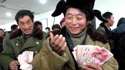 In this Dec. 29, 2006, file photo, Chinese migrant worker Zhang Guijun, foreground, reacts as he receives his delayed wages of 6,960 yuan in Shenyang, northern China's Liaoning province. Wage arrears are a major problem for Chinese laborers, especially migrants working on casual terms in the construction industry. Wages are supposed to be paid up before workers travel home for last month’s Lunar New Year holiday, but many contractors still fail to pay up.