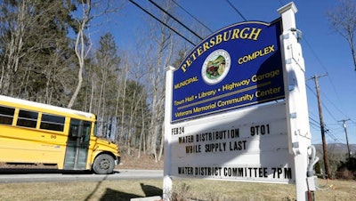 In this Friday, Feb. 26, 2016 photo, a sign outside the Petersburgh Municipal Complex informs residents of water distribution times in Petersburgh, N.Y. PFOA, long used in the manufacuring of Teflon pans, Gore-Tex jackets, ski wax, and many other products has turned up in the water in factory towns around the country like Petersburgh, impacting drinking water.