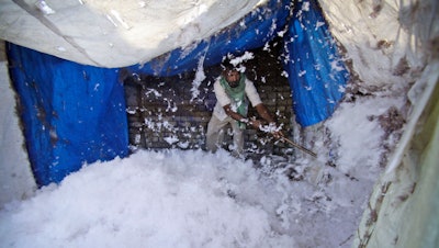 In this file photo, an Indian worker processes cotton at a factory on the outskirts of Jammu, India. U.S. seed giant Monsanto has threatened to pull its genetically modified crop technology from India if the government goes ahead with its plan to cut the company's royalty fees. Millions of small farmers have adopted genetically modified cotton seeds, making India one of the world's biggest producers of cotton.