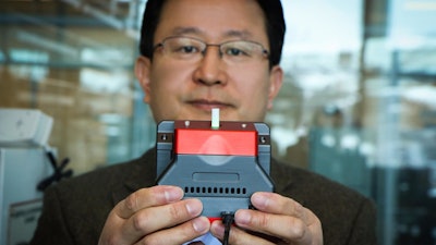 University of Utah materials science and engineering professor Ling Zang holds up a prototype handheld detector his company is producing that can sense explosive materials and toxic gases. His research team developed a new material for the detector that can sense alkane fuel, a key ingredient in such combustibles as gasoline, airplane fuel and homemade bombs.