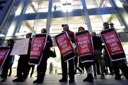 In this Tuesday, Feb. 23, 2016, file photo, protesters carry placards outside an Apple store in Boston. Tech companies, security experts and civil liberties groups are filing court briefs supporting Apple in its battle with the FBI. The groups oppose a judge’s order that would require Apple to help federal agents hack an encrypted iPhone used by a San Bernardino mass shooter.