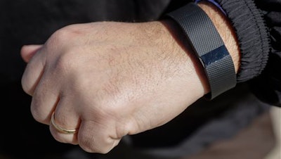 In this Monday, Feb. 29, 2016, photo, Brett Broviak, a manager of respiratory and sleep services at IU Health North Hospital, shows off his Fitbit fitness tracker for the camera on the hospital's campus in Carmel, Ind. Companies and insurers looking to reduce health-care costs are turning to incentives and may soon start rewarding you for wearing a fitness device that tracks your steps, heart rate and more.