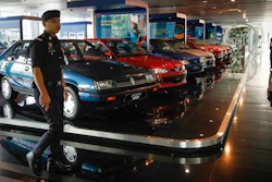 A Malaysian policeman walks by a fleet of national cars on display at the Proton Centre of Excellence Complex in Kuala Lumpur, Malaysia, Tuesday, March 1, 2016. Malaysian national car company Proton says it has begun shipping left-hand drive sedans to Chile as it seeks to tap new markets and revitalize exports.