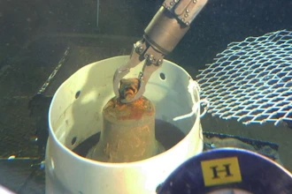 The manipulator arm of HURL's submersible places the I-400 bell into a collection basket.