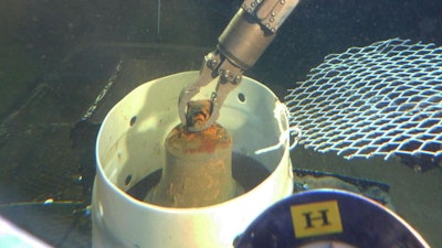 The manipulator arm of HURL's submersible places the I-400 bell into a collection basket.