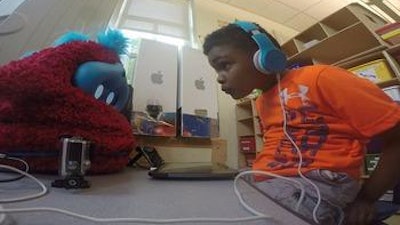A child plays an interactive language learning game with Tega, a socially assistive robot.