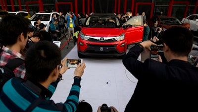 In this photo taken Monday, April 11, 2016, visitors examine the Yuan, BYD's latest Plug-in Hybrid mini SUV introduced at the BYD Dreams Conference in Beijing, China. Industry data released Tuesday, April 12, 2016 show that Chinese auto sales rose by nearly 10 percent last month, led by strong demand for SUVs that more than offset slipping passenger car sales.