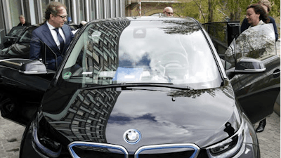 German Transportation Minister Alexander Dobrindt, left, and his staff members get in the minister's e-car after a press conference in Berlin, Germany, Wednesday, April 27, 2016. Germany plans to subsidize electric cars in a bid to help the country's auto industry compete in the global market for the growingly-popular and environmentally friendly vehicles.