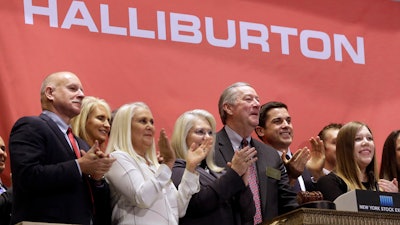 In this file photo, Halliburton Chairman, President and CEO David Lesar, third from right, rings the New York Stock Exchange opening bell. Halliburton and Baker Hughes announced their plan to combine in November 2014. The U.S. Justice Department is expected to sue to stop the acquisition, but the lawsuit had not yet been announced.