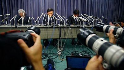 Mitsubishi Motors President Tetsuro Aikawa, center, listens to a reporter's question during a press conference in Tokyo, Wednesday, April 20, 2016. Mitsubishi Motors Corp. said Wednesday it used improper testing methods to make some of its vehicle models look more fuel efficient than they actually are.