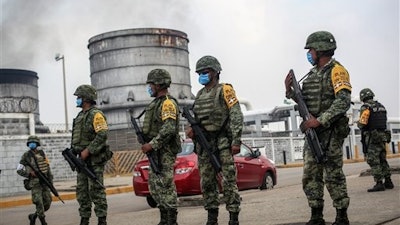 Mexican army soldiers wearing protective face masks stand guard at an entrance of the Pajaritos petrochemical complex in Coatzacoalcos, Mexico, Thursday, April, 21, 2016. At least 13 people are now confirmed dead and scores of others were injured in a Wednesday afternoon explosion inside the plant. The state oil company Petroleos Mexicanos, or Pemex, said the plant, operated by Mexichem, in partnership with Pemex, produces vinyl chloride, a hazardous industrial chemical.