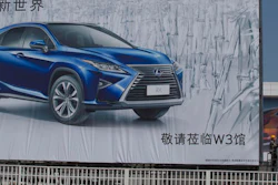 Workers labor near an ad for an SUV at the site of the upcoming Auto Show in Beijing, China, Wednesday, April 20, 2016. China's love affair with SUVs is helping to cushion the blow of an unexpectedly painful slump in the rest of its crowded auto market. Sales of SUVs, seen as the safest option on China’s rough, chaotic roads, soared 52 percent last year. That helped the overall market grow 7.3 percent - a sliver of its 45 percent peak in 2009 - even though car and minivan sales fell.
