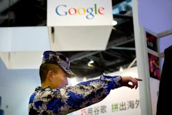 In this April 29, 2015, file photo, a security guard points while walking past a display booth for Google at the Global Mobile Internet Conference in Beijing. The American government has cited on Friday, April, 2016, that Chinese Internet controls as a trade barrier in a report that comes as Beijing tries to block its public from seeing news about the finances of Chinese leaders' families.