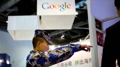 In this April 29, 2015, file photo, a security guard points while walking past a display booth for Google at the Global Mobile Internet Conference in Beijing. The American government has cited on Friday, April, 2016, that Chinese Internet controls as a trade barrier in a report that comes as Beijing tries to block its public from seeing news about the finances of Chinese leaders' families.