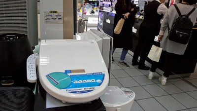 Shoppers stand near a smart toilet seat cover on display at a shopping mall in Beijing, China, Wednesday, April 20, 2016. The Chinese government's latest plan to perk up its slowing economy is based on the humble rice cooker and luxury toilet seats.