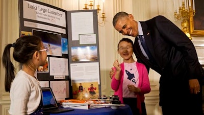 President Barack Obama laughs as he hugs Rebecca Yeung, 11, from Seattle, Wash., next to her sister Kimberly Yeung, 9, as they show him their homemade “spacecraft” that features a photograph of their late cat and is made of archery arrows and wood scraps which they launched into the stratosphere via a helium balloon that records location coordinates, temperature, velocity, and pressure and reports the data back to the them, Wednesday, April 13, 2016, during the 2016 White House Science Fair at the White House in Washington.