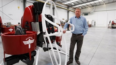 In this Feb. 9, 2016 photo, Martin Aircraft CEO Peter Coker stands next to a Martin Jetpack in Christchurch, New Zealand. The company says it’s close to commercial liftoff, but the man who started it fears his vision of a personal jetpack will remain grounded.