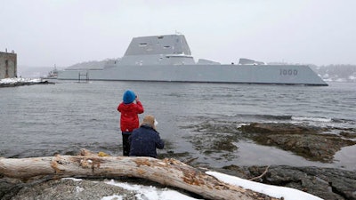 In this March 21, 2016 file photo, Dave Cleaveland and his son, Cody, photograph the USS Zumwalt as it passes Fort Popham at the mouth of the Kennebec River in Phippsburg, Maine, as it heads to sea for final builder trials. The ship is so stealthy that the U.S. Navy resorted to putting reflective material on its halyard to make it visible to mariners during the trials.