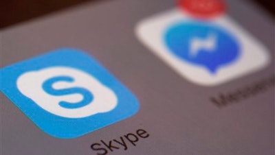 This Saturday, April 9, 2016 photo shows the icons for Microsoft's Skype and Facebook's Messenger apps on a smartphone in New York. In coming months, people who use Messenger, Skype and Canada's Kik for online chats can expect to see all kinds of businesses offering information and other services with the help of messaging 'bots,' or software that’s capable of human-like conversation.