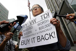 Joyce Ertel Hulbert, owner of a 2015 Volkswagen Golf TDI, holds a sign while interviewed outside of the Phillip Burton Federal Building in San Francisco, Thursday, April 21, 2016. An agreement will give consumers who bought nearly 600,000 Volkswagen vehicles rigged to cheat on emissions tests the option of having the automaker buy back the cars or fix them, a judge said Thursday.