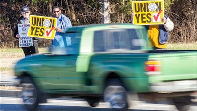 In this Dec. 4, 2015 file photo, union supporters hold up signs near the Volkswagen plant in Chattanooga, Tenn. Volkswagen announced on Monday, April 25, 2016, that it plans to appeal a National Labor Relations Board decision upholding a union vote by skilled-trades workers at the plant.
