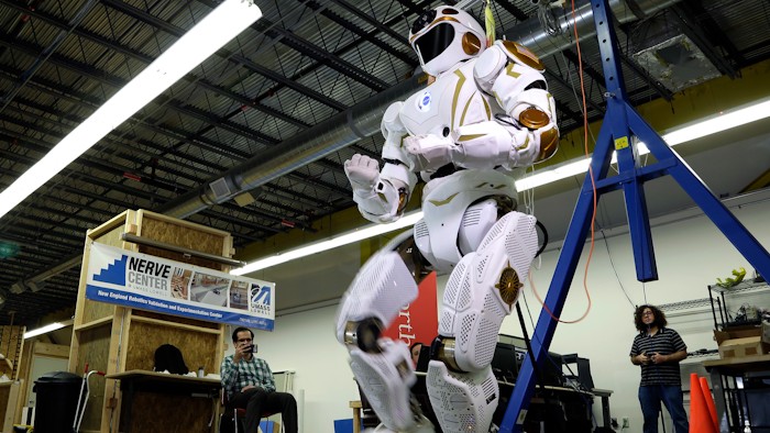 In this May 2, 2016 photo, researchers watch the six-foot-tall, 300-pound Valkyrie robot walk slowly at University of Massachusetts-Lowell's robotics center in Lowell, Mass. 'Val,' one of four sister robots built by NASA, could be the vanguard for the colonization of Mars by helping to set up a habitat for future human explorers.