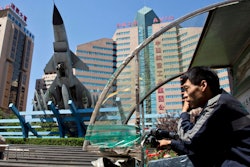 A delivery man talks on his phone as he rides past the headquarters of Aviation Industry Corp. in Beijing. AVIC is a state-owned corporate colossus. Several months earlier, Tang Energy Group, of Dallas, won an arbitration case arising from a contract with AVIC. But AVIC has challenged the ruling in federal court, arguing that as an arm of the Chinese government, it isn't subject to American arbitrators.