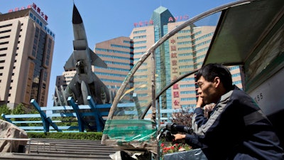 A delivery man talks on his phone as he rides past the headquarters of Aviation Industry Corp. in Beijing. AVIC is a state-owned corporate colossus. Several months earlier, Tang Energy Group, of Dallas, won an arbitration case arising from a contract with AVIC. But AVIC has challenged the ruling in federal court, arguing that as an arm of the Chinese government, it isn't subject to American arbitrators.