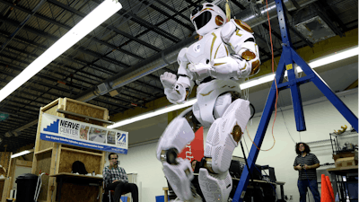 In this May 2, 2016 photo, researchers watch the six-foot-tall, 300-pound Valkyrie robot walk slowly at University of Massachusetts-Lowell's robotics center in Lowell, Mass. 'Val,' one of four sister robots built by NASA, could be the vanguard for the colonization of Mars by helping to set up a habitat for future human explorers.