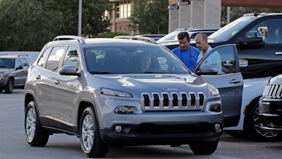 In this AP photo, salesperson Jerry Camero, right, delivers a 2016 Jeep Cherokee Limited to a customer. Major automakers reported sales figures on Tuesday, May 3, 2016.