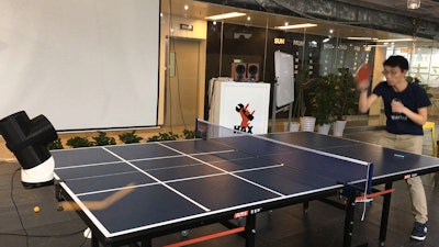 Harrison Chen plays ping pong with the robotic table tennis trainer prototype in Shenzhen, China.