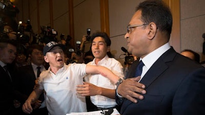 A relative of a victim in the British disinfectant case complains to Ata Safdar, head of British firm Reckitt Benckiser Korea, right, during a press conference in Seoul, South Korea, Monday, May 2, 2016. British consumer goods company Reckitt Benckiser has apologized and accepted responsibility for selling deadly disinfectants that killed or injured about 180 people.