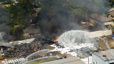 Firefighters pour water on a four-alarm fire at a custom packing and filling company in west Houston. The blaze caused various explosions that rattled the industrial area and surrounding neighborhoods.