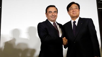 Nissan Motor Co. President and CEO Carlos Ghosn, left, and Mitsubishi Motors Corp. Chairman and CEO Osamu Masuko pose for photographers after their joint press conference at the Nissan headquarters in Yokohama, near Tokyo. Nissan is taking a 34 percent stake in scandal-ridden Mitsubishi Motors in what Ghosn said was 'a win-win' deal.