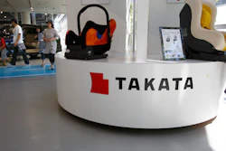 In this Wednesday, May 4, 2016 photo, a family walk by child seats manufactured by Japanese auto parts maker Takata Corp. at an automaker's showroom in Tokyo. Takata, which also makes seat belts, is expecting a loss instead of a profit for the fiscal year that ended in March because of ballooning costs from a massive global air-bag recall. Takata is projecting an annual net loss of $120 million.