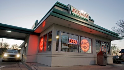 In this file photo, a customer picks up doughnuts at the drive through at a Krispy Kreme store in Matthews, N.C. Krispy Kreme is being taken private by JAB Beech.