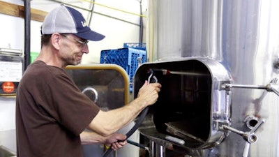 Thunder Island Brewery head brewer Brian Perkey hoses out a vat as he talks about Nestle moving a water bottling plant into the small community in Cascade Locks, Ore. The proposal for Nestle to build a water bottling plant in Cascade Locks is set to be one of the most heated battles in the state’s May 17 primary. Town leaders and some residents want it, but others are fiercely opposed.