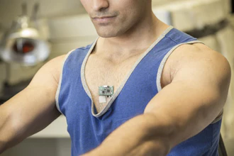 Study co-author Amay Bandodkar wears the ChemPhys patch while using an exercise bike in a lab at the Center for Wearable Sensors.