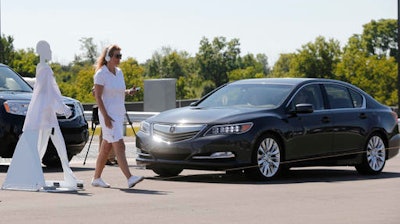 In this July 20, 2015 file photo, a pedestrian crosses in front of a vehicle as part of a demonstration at Mcity, used to test driverless and connected vehicles, on the University of Michigan campus in Ann Arbor, Mich. The U.S. auto industry's home state of Michigan is preparing for the advent of self-driving cars by pushing legislation to allow for public sales and operation _ a significant expansion beyond an existing law that sanctions autonomous vehicles for testing only.